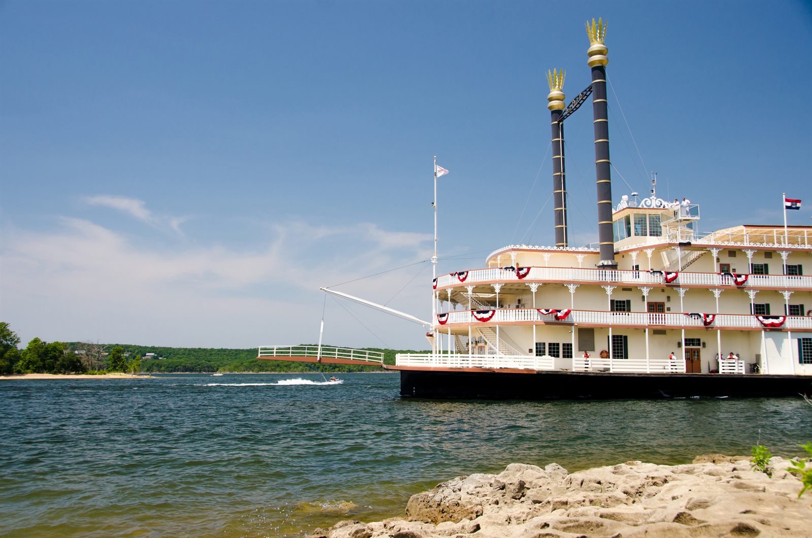 A white paddlewheel showboat with twin smokestacks on a lake in Branson, Missouri